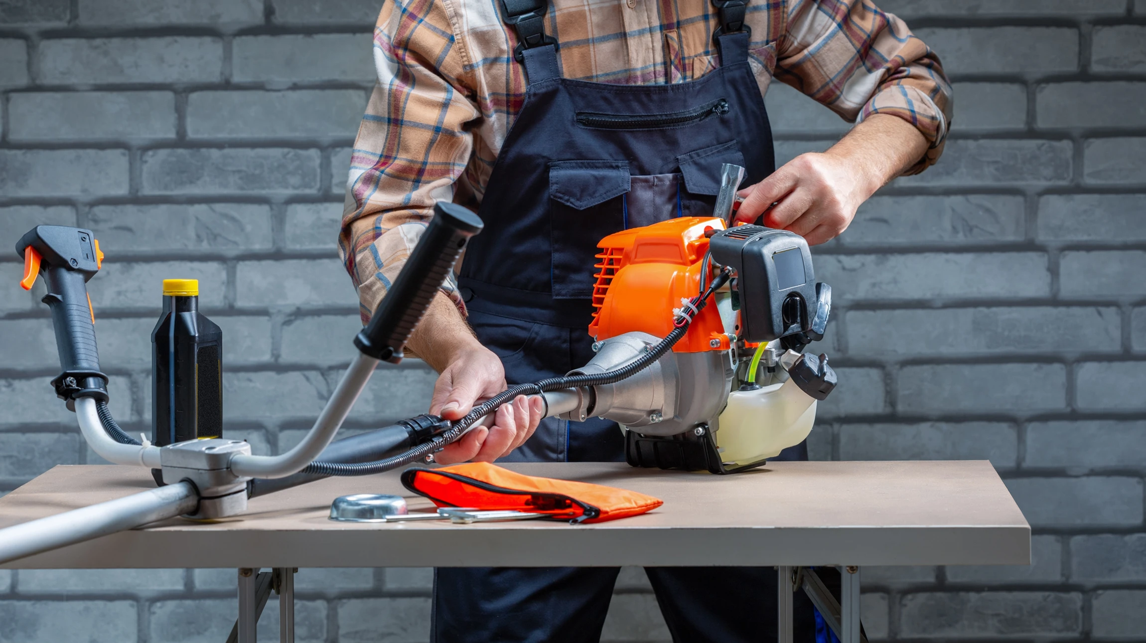 Photographie d'un atelier de motoculture professionnel. Un mécanicien en tenue de travail effectue l'entretien ou la réparation d'une tondeuse ou d'un engin de motoculture, penché sur la machine avec des outils à proximité. L'atelier doit montrer un environnement organisé avec des étagères contenant des pièces de rechange et du matériel de motoculture en arrière-plan. La scène doit transmettre la compétence technique et la confiance.
