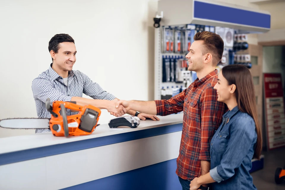 un client examine de nouveaux mod&egrave;les de tondeuses &agrave; gazon dans un magasin d'&eacute;lectricit&eacute; pour les jardiniers et les horticulteurs